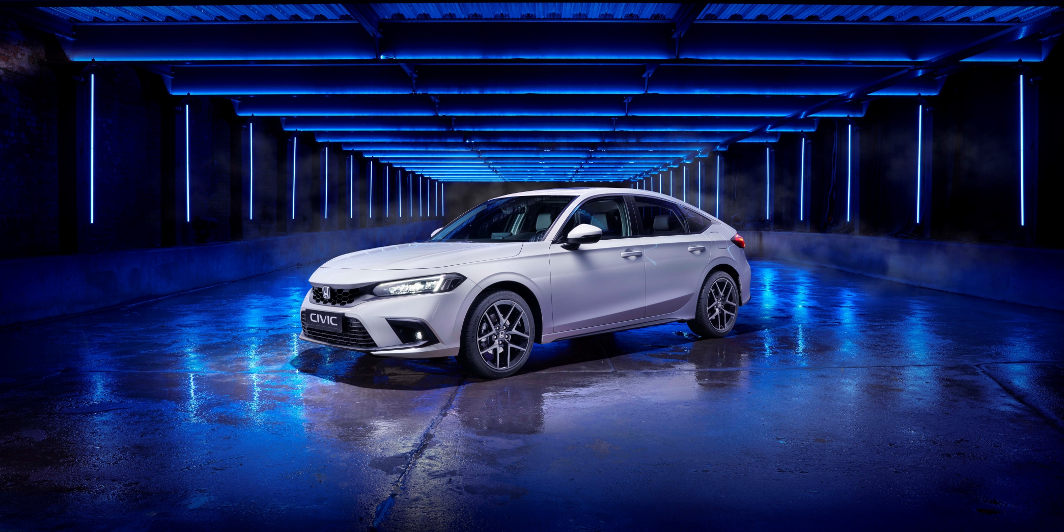 Vue de trois quarts avant d'une nouvelle Honda Civic 2022 blanche et prise en photo en studio avec un éclairage bleuté